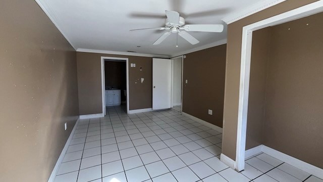 empty room with ceiling fan, ornamental molding, and light tile patterned floors