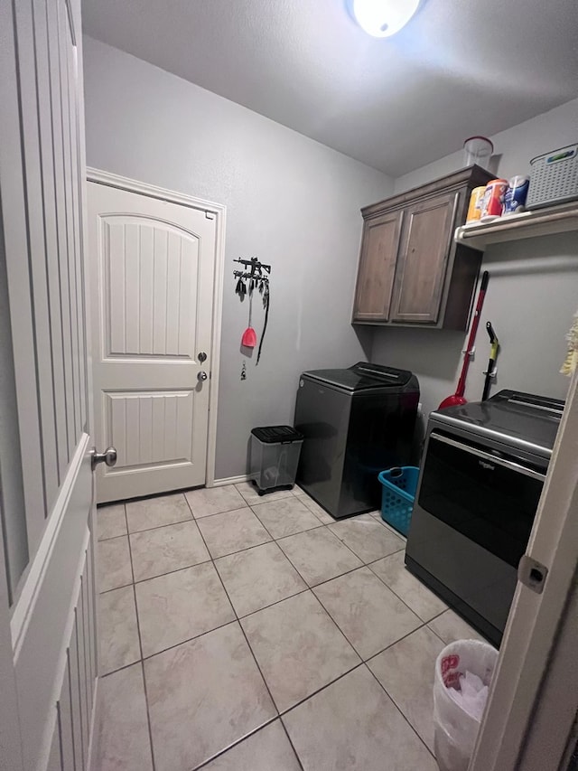 laundry area with cabinets, independent washer and dryer, and light tile patterned flooring