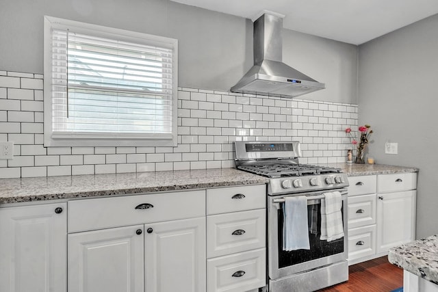 1722 Purdue Ave, Big Spring, TX 79720 - kitchen featuring stainless steel gas stove, wall chimney exhaust hood, decorative backsplash, and white cabinetry