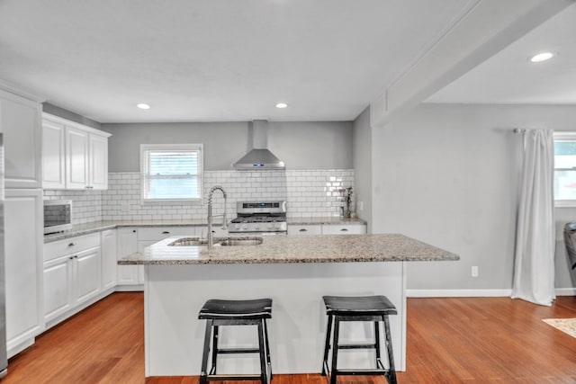 1722 Purdue Ave, Big Spring, TX 79720 - kitchen with wall chimney range hood, stainless steel range with gas stovetop, a sink, white cabinetry, and recessed lighting