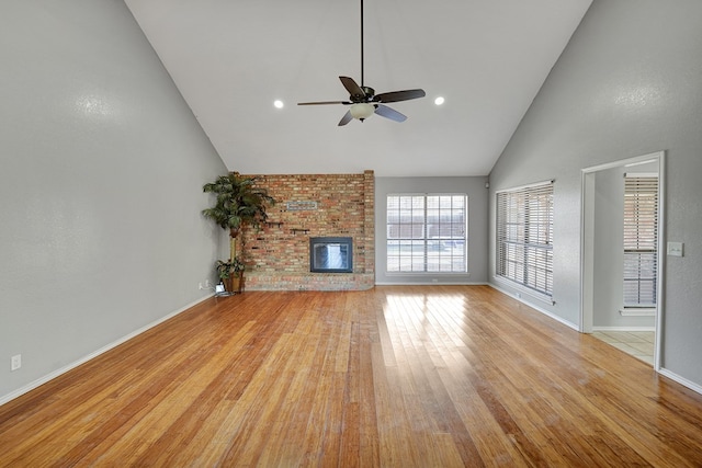 unfurnished living room featuring baseboards, light wood-style flooring, a fireplace, high vaulted ceiling, and a ceiling fan