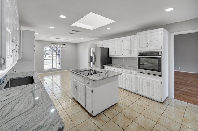 kitchen with a sink, light tile patterned floors, light stone countertops, and stainless steel appliances