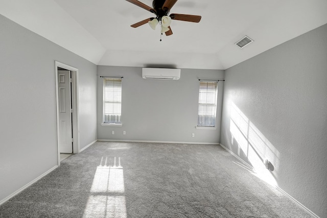 empty room with visible vents, lofted ceiling, a healthy amount of sunlight, and a wall unit AC