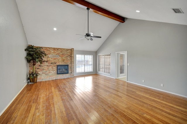 unfurnished living room with beamed ceiling, light wood-style flooring, a brick fireplace, and high vaulted ceiling