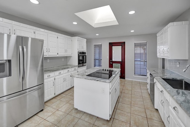 kitchen with a skylight, recessed lighting, a sink, appliances with stainless steel finishes, and a center island