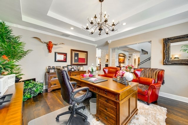 office space featuring ornamental molding, dark hardwood / wood-style floors, a raised ceiling, and a notable chandelier