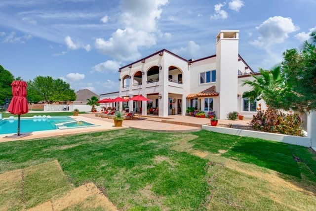 back of house with a lawn, a balcony, and a patio