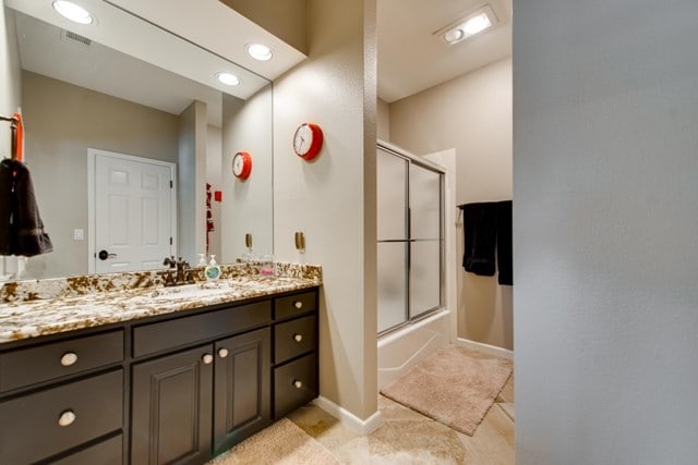 bathroom featuring tile patterned flooring, vanity, and combined bath / shower with glass door