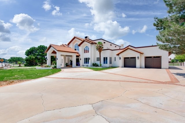 mediterranean / spanish-style house featuring a garage and a front lawn