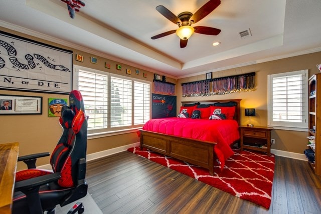 bedroom with a raised ceiling, ceiling fan, dark hardwood / wood-style floors, and ornamental molding