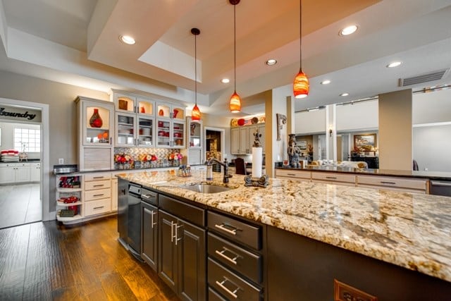 kitchen featuring a raised ceiling, sink, decorative light fixtures, dark brown cabinets, and dark hardwood / wood-style flooring