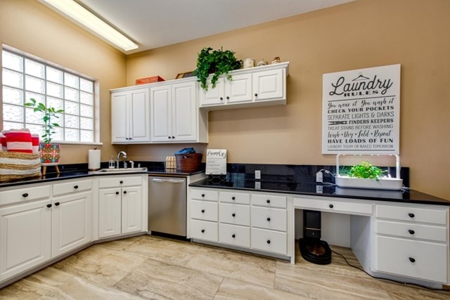 kitchen featuring white cabinets, dishwasher, and sink