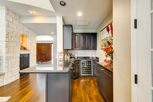 kitchen featuring dark hardwood / wood-style floors, dark brown cabinets, a kitchen island, a kitchen bar, and beverage cooler