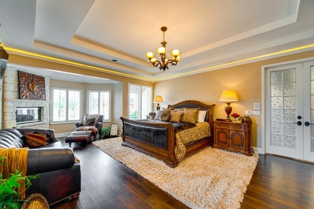 bedroom featuring dark hardwood / wood-style flooring, a raised ceiling, and a notable chandelier