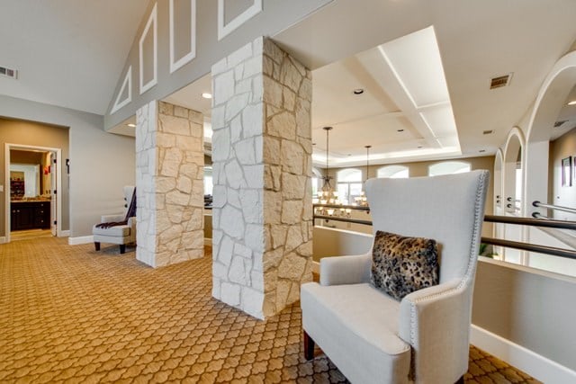 living area with ornate columns and carpet floors