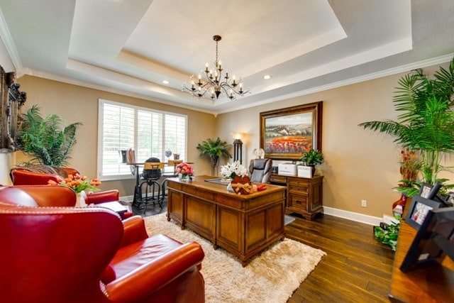 office with a tray ceiling, a chandelier, dark wood-type flooring, and ornamental molding