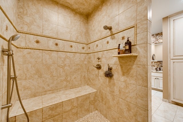 bathroom featuring tile patterned floors, a tile shower, and backsplash