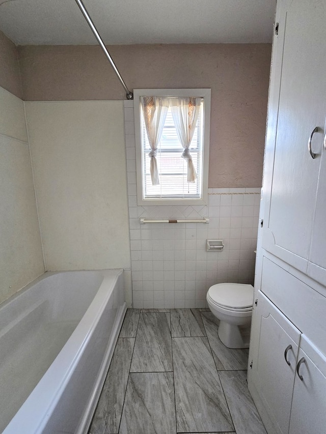 bathroom with shower / bath combination, toilet, and tile walls