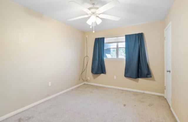 spare room with light colored carpet, ceiling fan, and baseboards