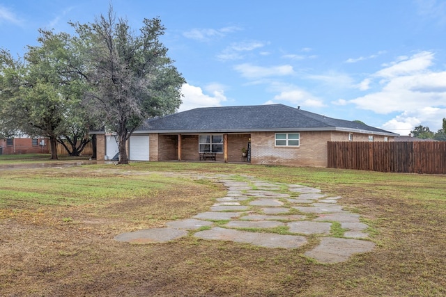 ranch-style home with a garage, brick siding, fence, and a front yard