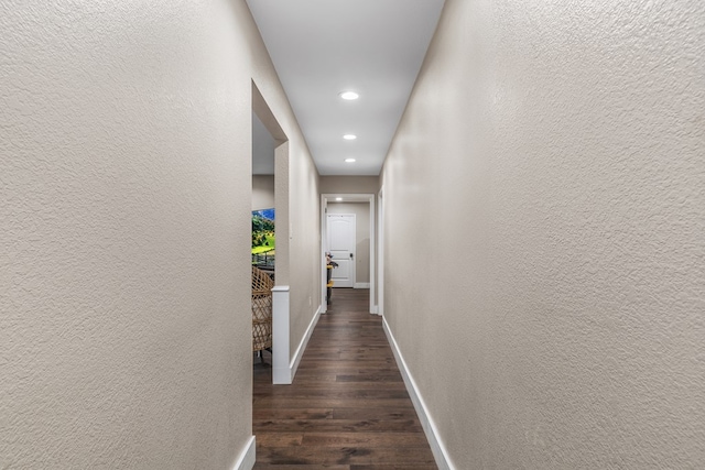 hall featuring recessed lighting, baseboards, dark wood finished floors, and a textured wall