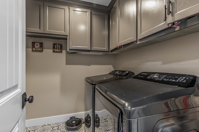 washroom featuring separate washer and dryer, cabinet space, and baseboards