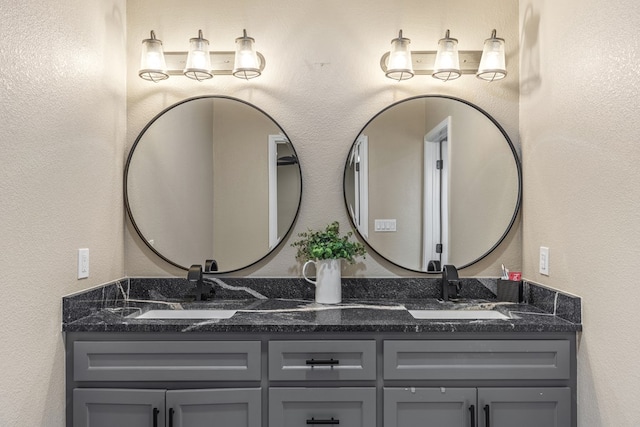 bathroom with a textured wall, a sink, and double vanity