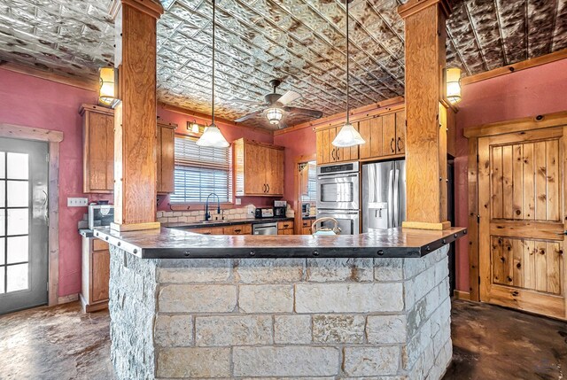 10500 E County Rd 90, Midland, TX 79706 - kitchen with stainless steel appliances, dark countertops, brown cabinetry, ceiling fan, and a sink