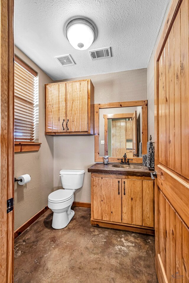 10500 E County Rd 90, Midland, TX 79706 - half bathroom with toilet, vanity, baseboards, unfinished concrete flooring, and a textured ceiling