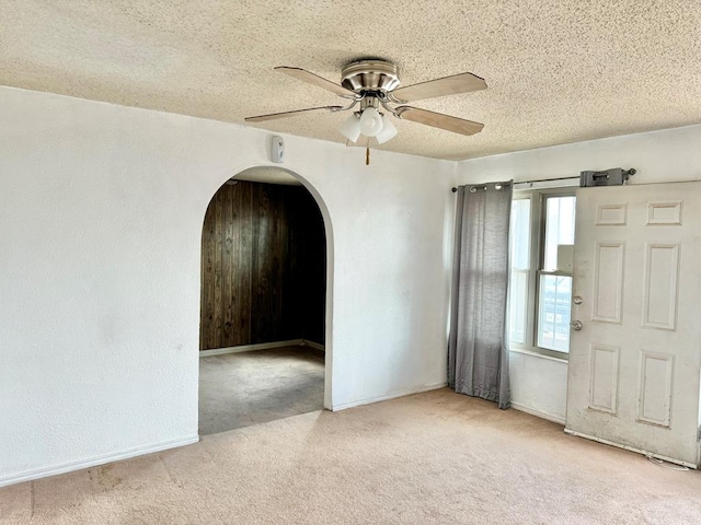 empty room with ceiling fan, light colored carpet, and a textured ceiling