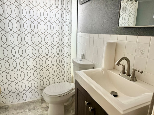 bathroom with vanity, toilet, and tile walls