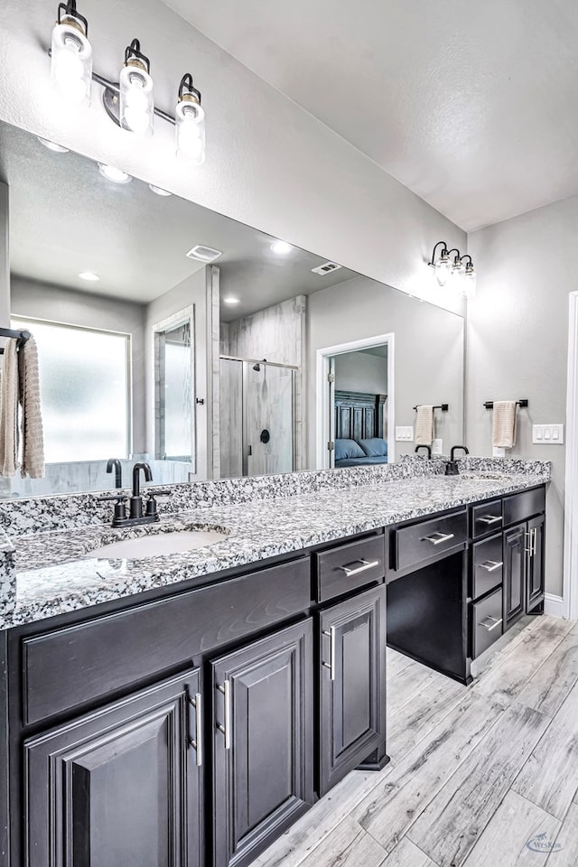6003 Sunny Stone Dr, Midland, TX 79705 - bathroom featuring a stall shower, double vanity, and wood finished floors