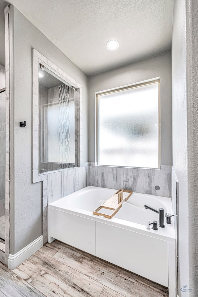 6003 Sunny Stone Dr, Midland, TX 79705 - full bath with a bath, wood finished floors, a textured ceiling, and a textured wall