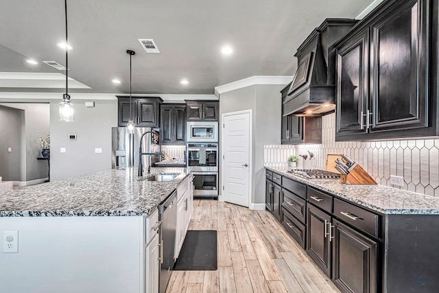 6003 Sunny Stone Dr, Midland, TX 79705 - kitchen with appliances with stainless steel finishes, backsplash, light wood-type flooring, light stone counters, and dark cabinetry
