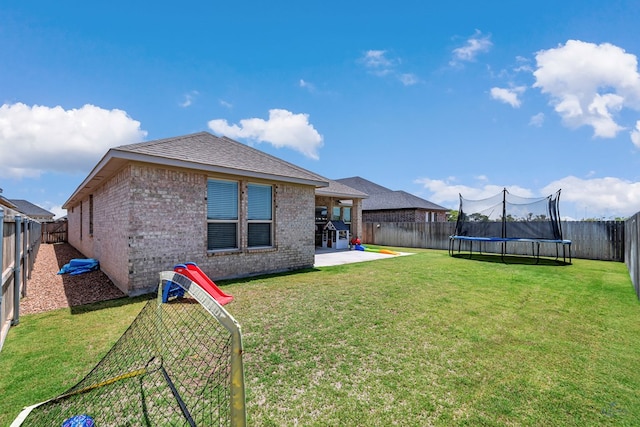 6003 Sunny Stone Dr, Midland, TX 79705 - rear view of property featuring brick siding, a patio area, a trampoline, a fenced backyard, and roof with shingles