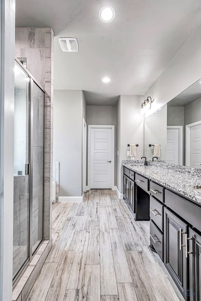 6003 Sunny Stone Dr, Midland, TX 79705 - full bath with double vanity, a shower stall, wood finished floors, and recessed lighting