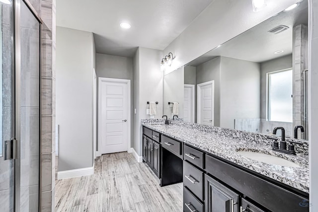 6003 Sunny Stone Dr, Midland, TX 79705 - bathroom featuring double vanity, wood finished floors, and a stall shower