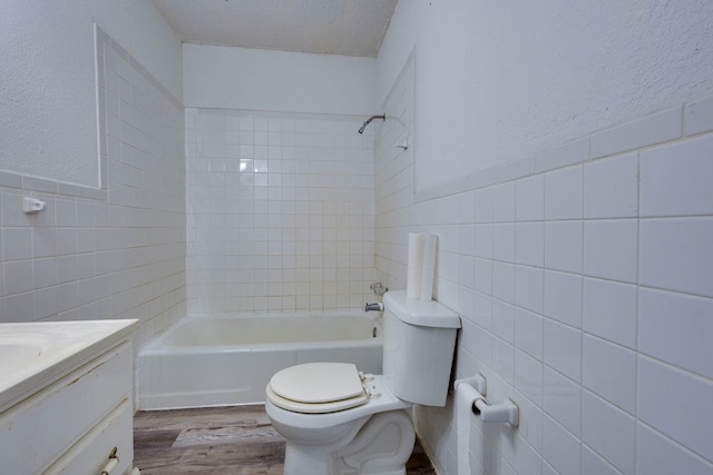 107 W 10th St, Big Spring, TX 79720 - bathroom featuring tile walls, vanity, wood finished floors, washtub / shower combination, and a wainscoted wall
