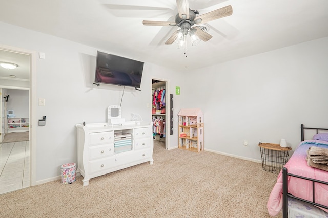 bedroom with a spacious closet, light colored carpet, and ceiling fan