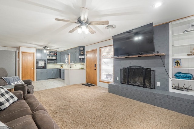 tiled living room featuring a brick fireplace, ceiling fan, and sink