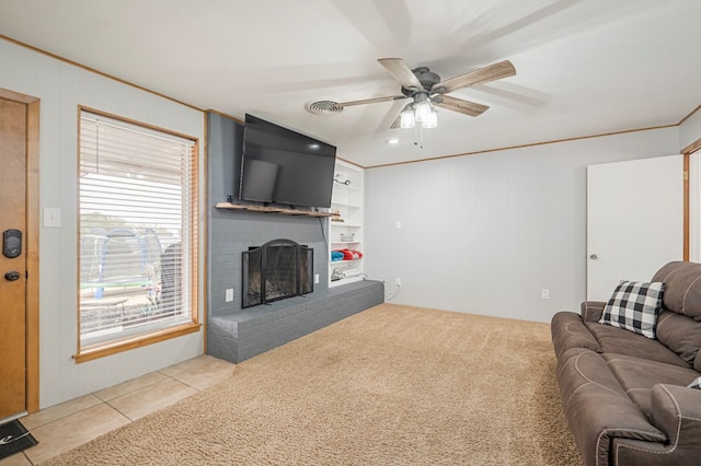 carpeted living room featuring ceiling fan, built in shelves, and a fireplace