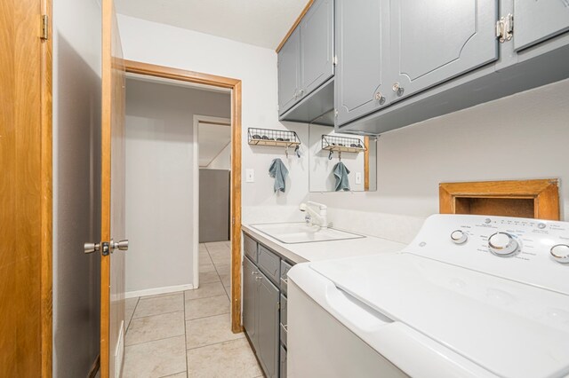 washroom featuring light tile patterned floors, sink, washing machine and clothes dryer, and cabinets