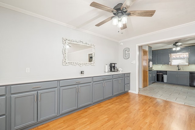 interior space with gray cabinetry, black appliances, light hardwood / wood-style floors, ornamental molding, and sink