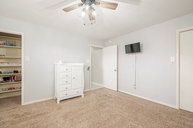 unfurnished bedroom with a spacious closet, light colored carpet, ceiling fan, and a closet