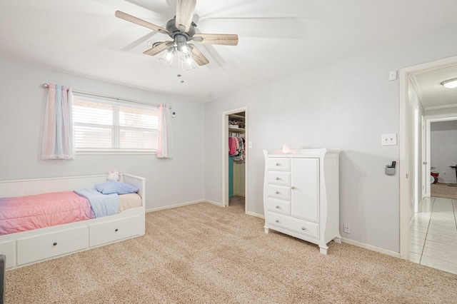 bedroom with ceiling fan, a closet, a walk in closet, and light colored carpet