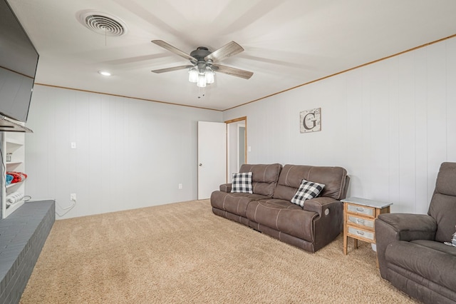 carpeted living room with crown molding and ceiling fan