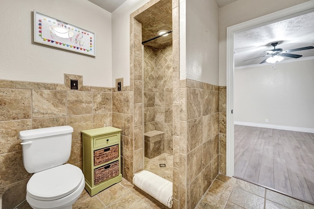 2406 Stutz Pl, Midland, TX 79705 - full bathroom featuring tiled shower, tile walls, a ceiling fan, and wainscoting