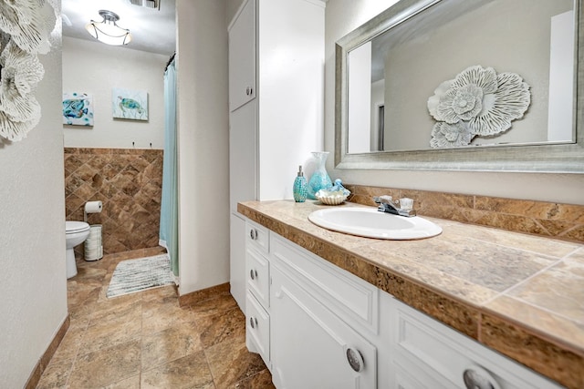 2406 Stutz Pl, Midland, TX 79705 - bathroom featuring vanity, stone finish floors, tile walls, and curtained shower