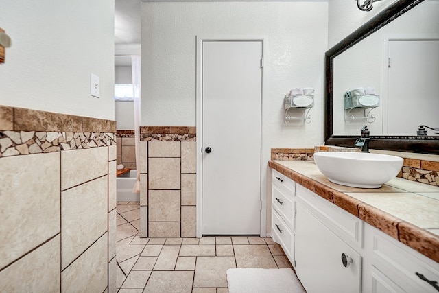 2406 Stutz Pl, Midland, TX 79705 - bathroom with vanity, tile walls, a tub, tile patterned flooring, and wainscoting