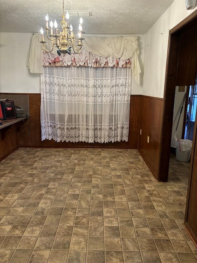 297 County Rd 221, Snyder, TX 79549 - dining area featuring a chandelier, wooden walls, a textured ceiling, and wainscoting